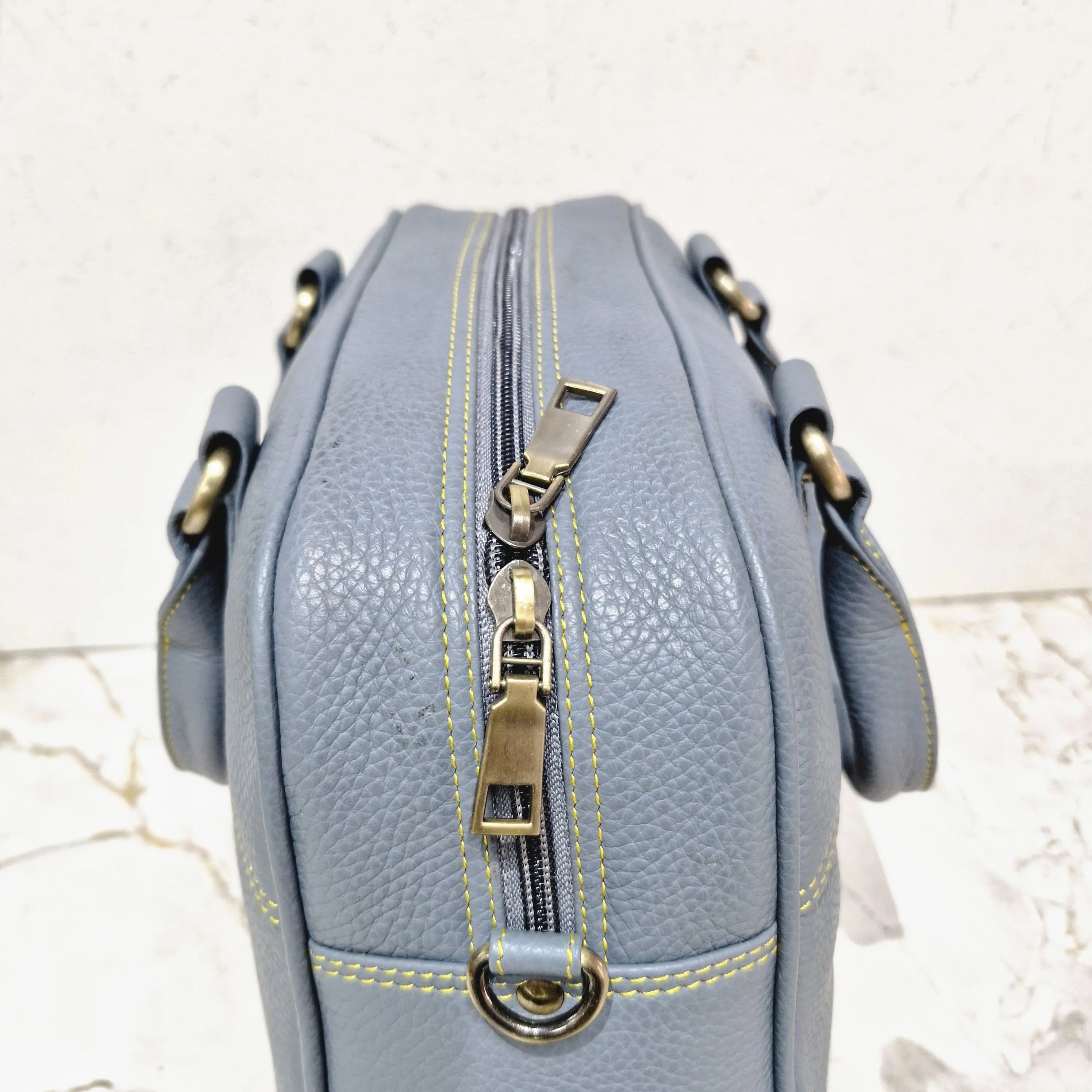 Blue genuine leather designer mini tote handbag with yellow contrast stitching, dual brass zipper, and top handles.