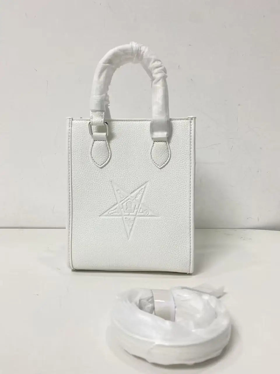 White genuine leather designer crossbody bag with embossed Order of the Eastern Star emblem and top handle.