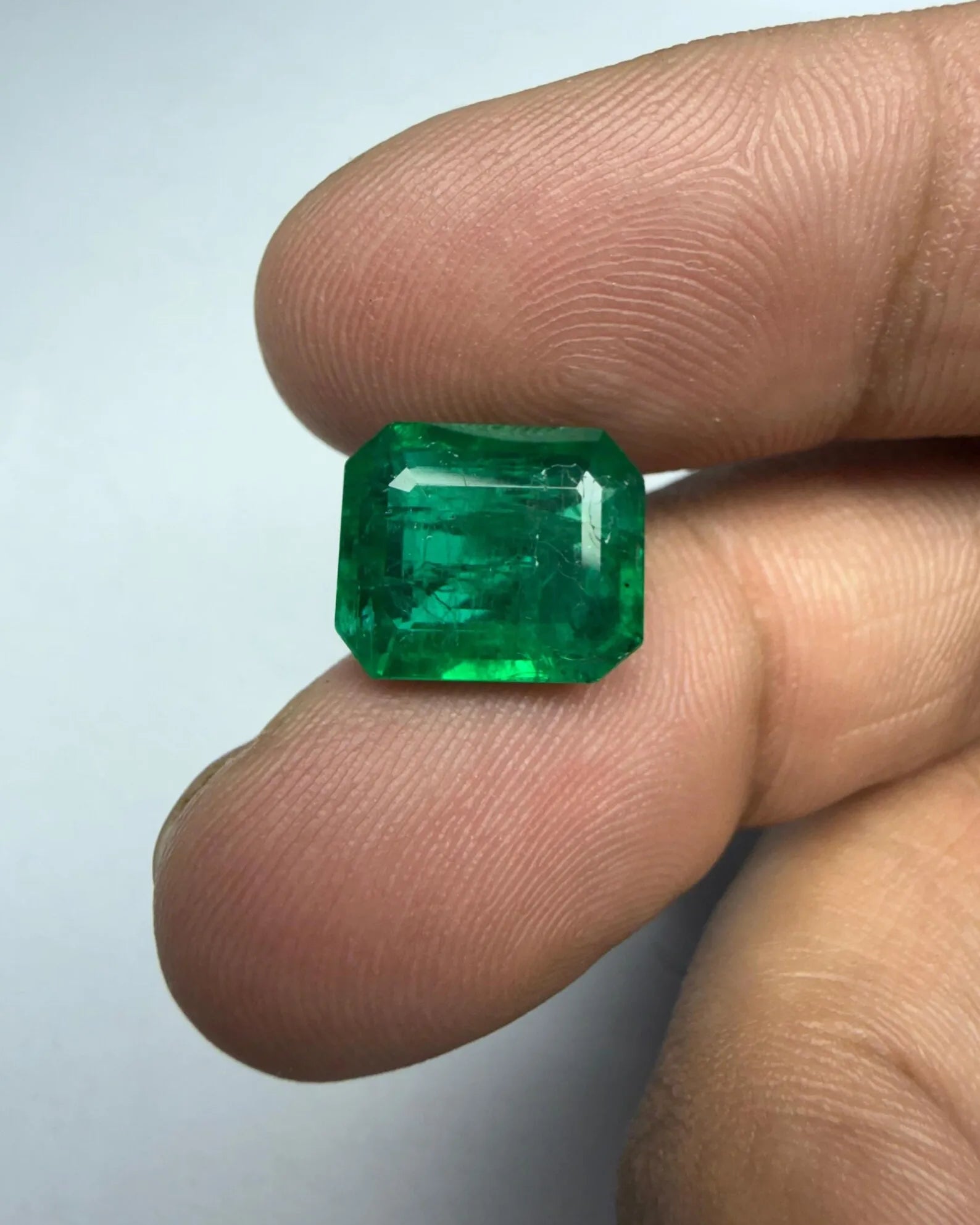 Green emerald-cut octagon gemstone facing camera, tablet and steps clearly defined
