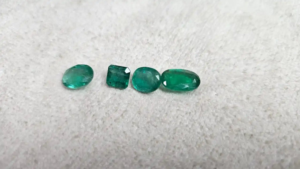 Loose green emerald-cut gemstone mix, five small stones on felt in a line