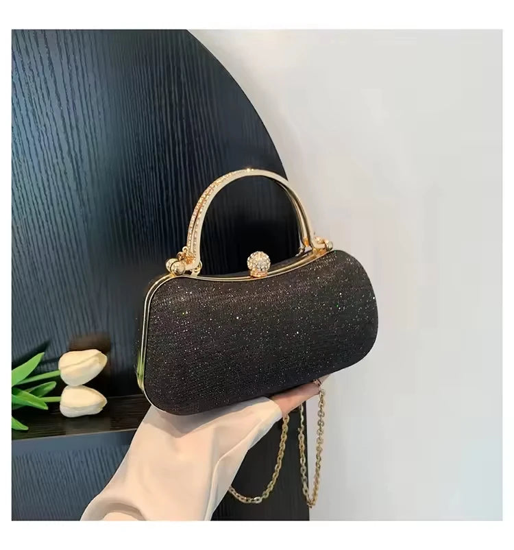 Black glitter evening clutch with crystal-encrusted handle, gold hardware, and chain strap for wedding party wear.