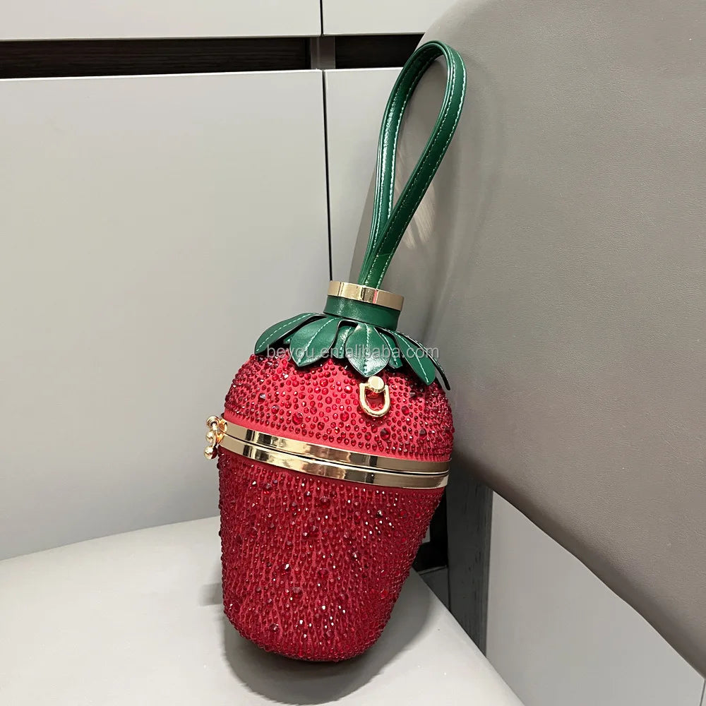 Luxury red rhinestone strawberry evening clutch with green leaf top, gold accents, and a green wrist handle.