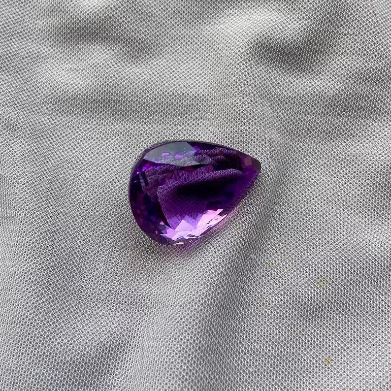 Amethyst teardrop gemstone with medium-deep purple hue and glossy facet reflections
