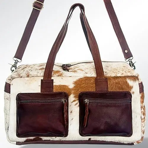 Handmade vintage western duffel bag in white and brown cowhide leather with two front pockets and brown leather straps.