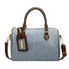 Light blue denim designer cylinder handbag with brown leather handles, shoulder strap, and branded luggage tag.