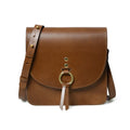 Tan leather designer crossbody handbag with brass ring hardware, adjustable strap, and modern minimalist style.