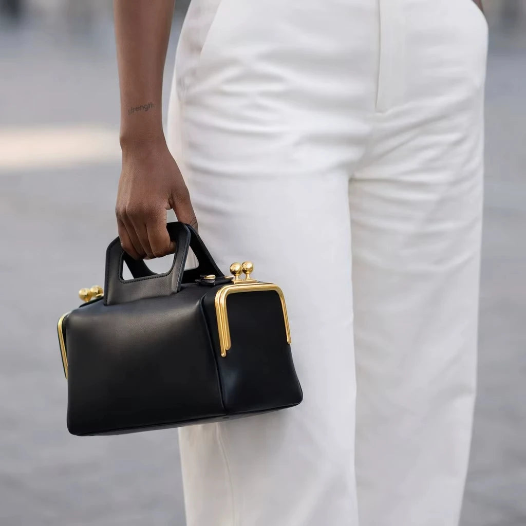 Black retro PU leather pillow bag with gold metal clasp accents, a stylish designer handbag for summer shoulder wear.