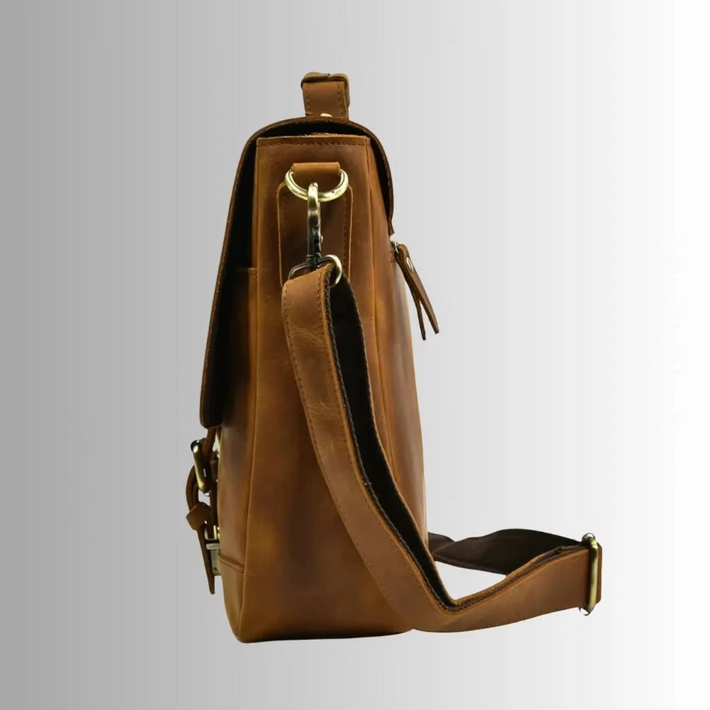 Tan leather business laptop briefcase for men, featuring a shoulder strap, brass hardware, and professional trunk style.