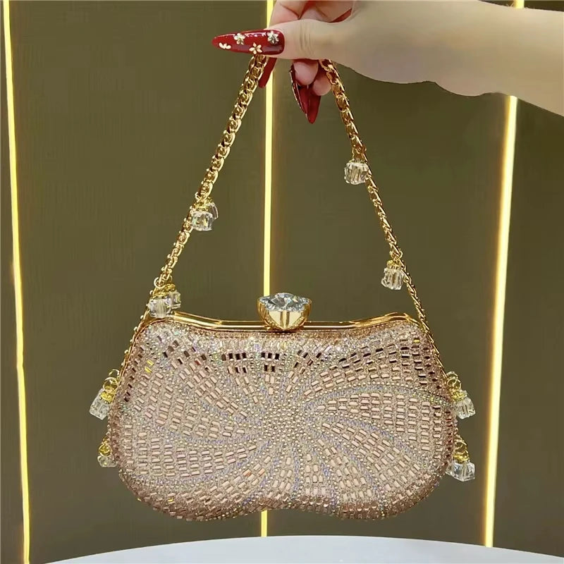 Rose gold crystal-embellished designer clutch with a gold chain strap, crystal clasp, and dangling decorative charms.