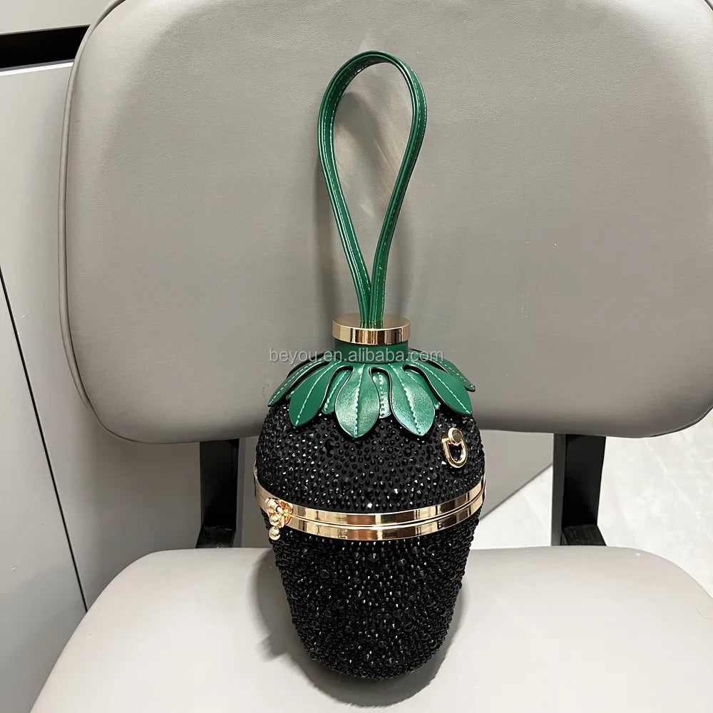 Black rhinestone strawberry evening bag with green leaf top, gold accents, and wrist handle. Designer luxury purse.