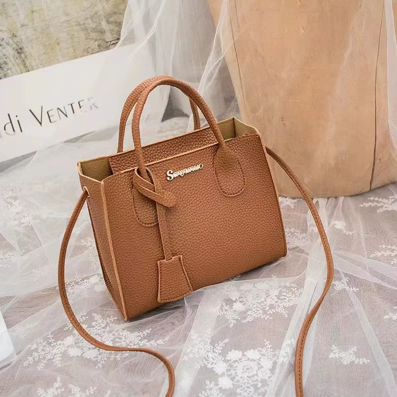 Brown pebbled PU leather designer handbag with dual handles, detachable shoulder strap, and gold-tone logo hardware.