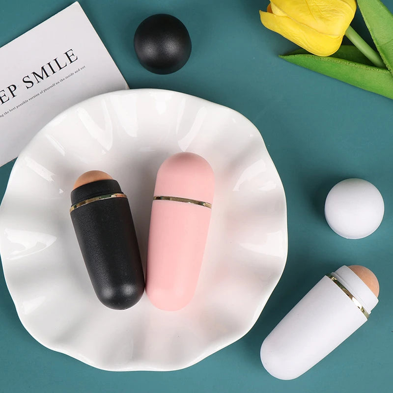 Black, pink, and white volcanic stone face oil-absorbing rollers with gold trim, arranged on a white plate.