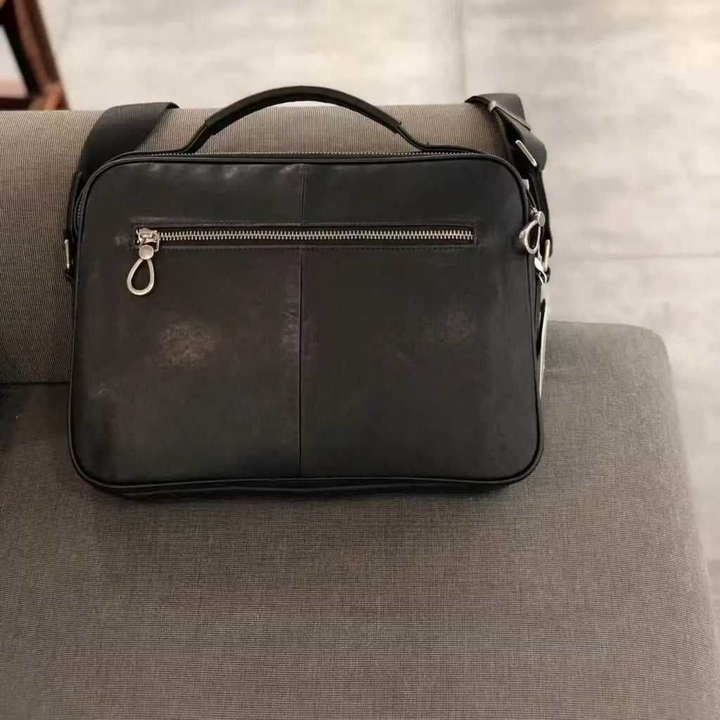 Black vintage cowhide leather messenger bag with horizontal zipper pocket, top handle, and adjustable shoulder strap.