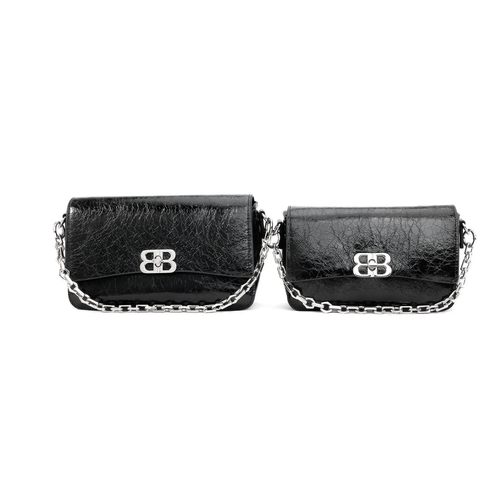 Two black crinkled leather designer clutch bags with silver chain straps and metallic clasp closures.