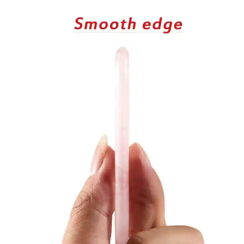 A hand holding a thin, smooth-edged pink rose quartz gua sha tool against a white background.