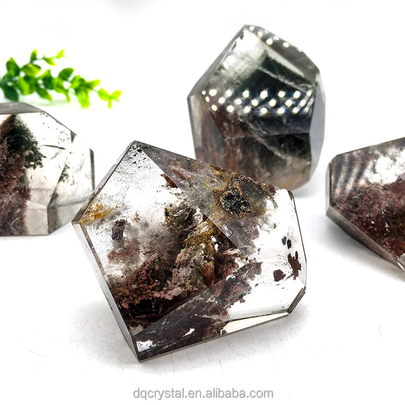 Polished clear quartz free-form crystal with dark mineral flecks and reddish-brown patches