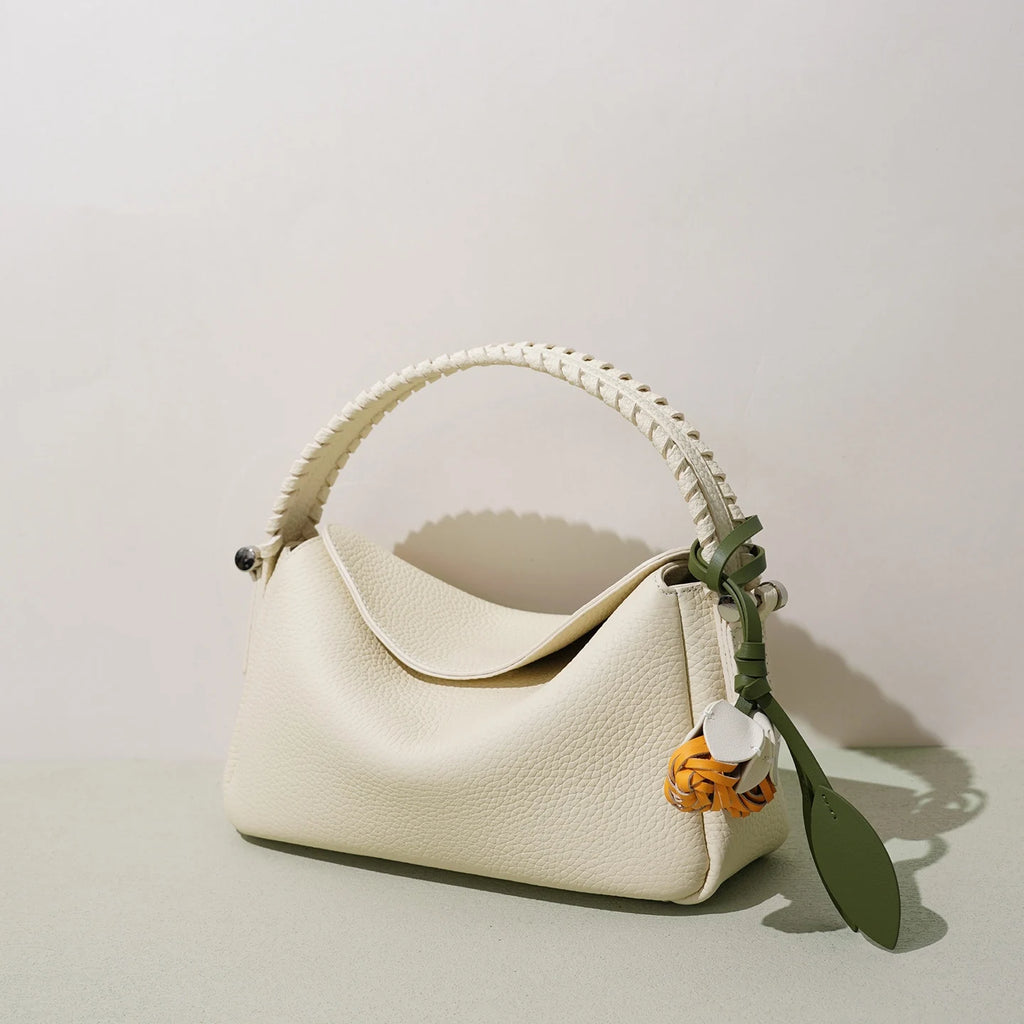 Off-white genuine leather designer handbag with woven top handle, olive green charm, and crossbody shoulder strap.