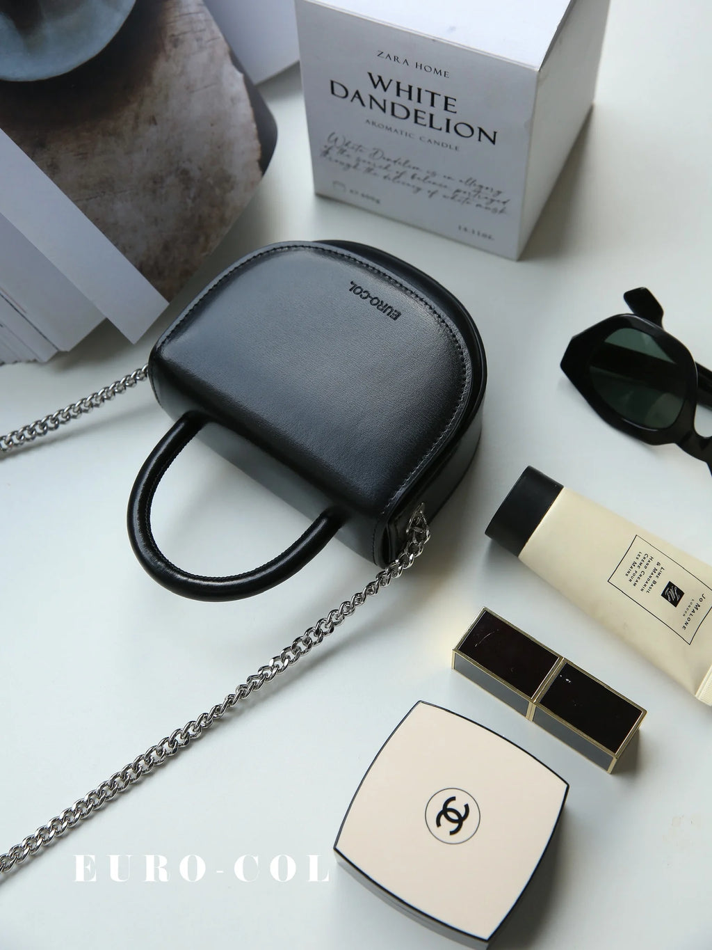Black cowhide leather mini evening clutch with top handle and silver chain strap for weddings and parties.