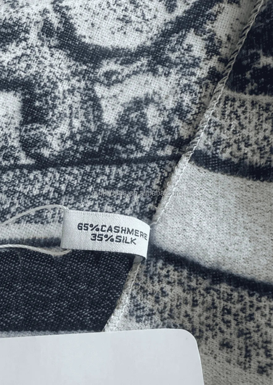 Luxury cashmere-silk blend scarf in black and white with a textured abstract print pattern and brand care tag.
