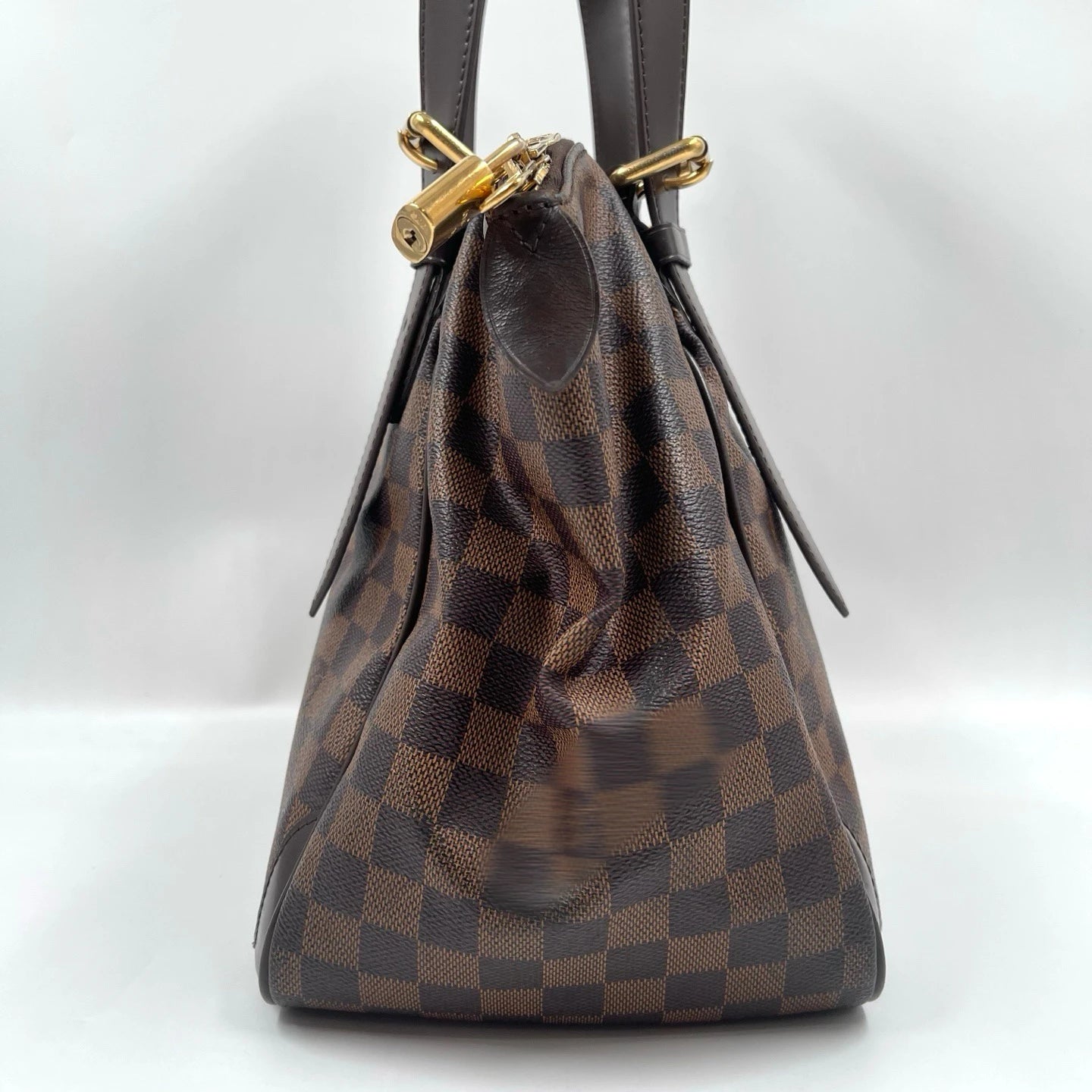 Luxury designer handbag in brown checkered canvas with leather straps and gold padlock hardware, unisex shoulder bag.