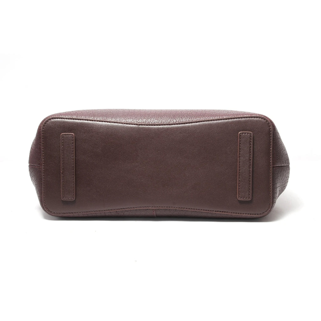 Bottom view of dark brown genuine leather designer handbag with protective feet and textured base.