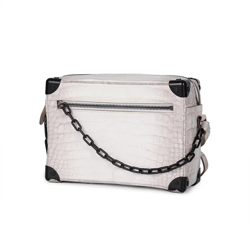 Off-white Himalayan crocodile leather trunk handbag with black metal corner accents and a decorative chain link strap.