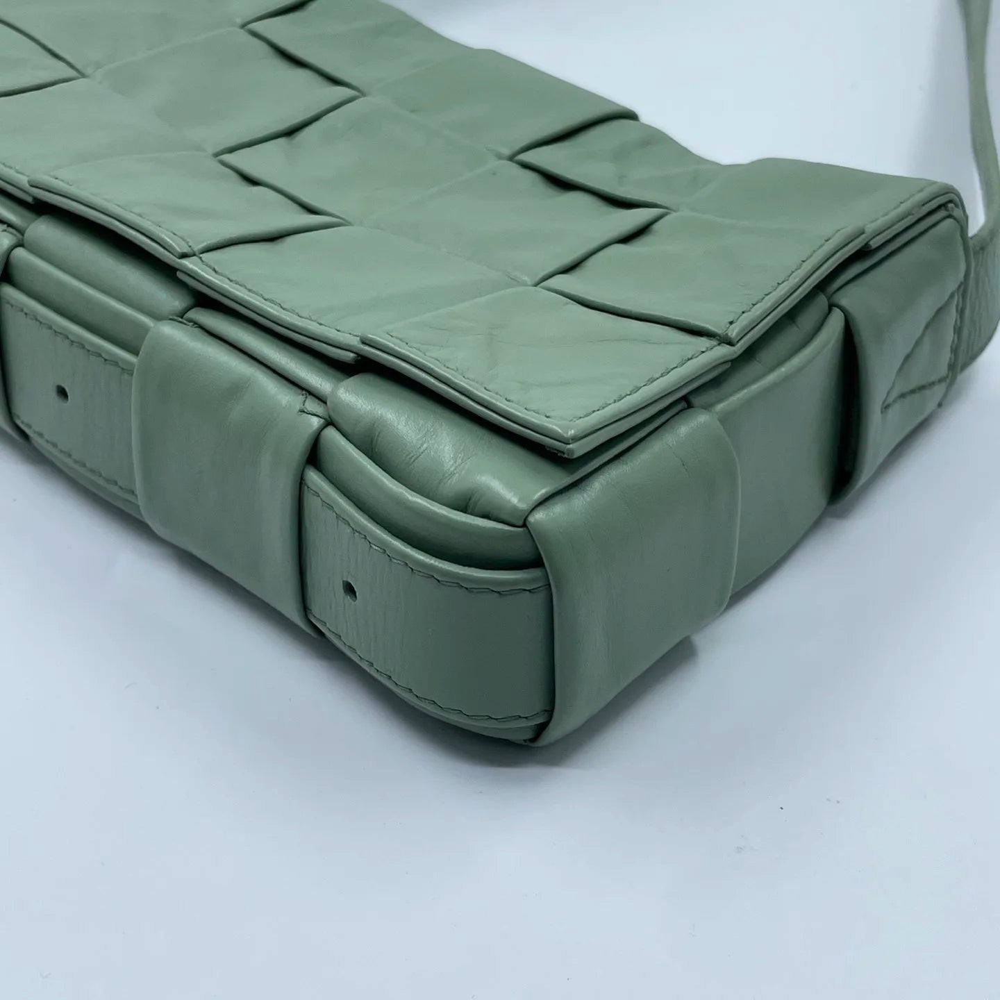 Light green designer shoulder bag in woven leather. Luxury pre-owned handbag with square weave pattern and strap.