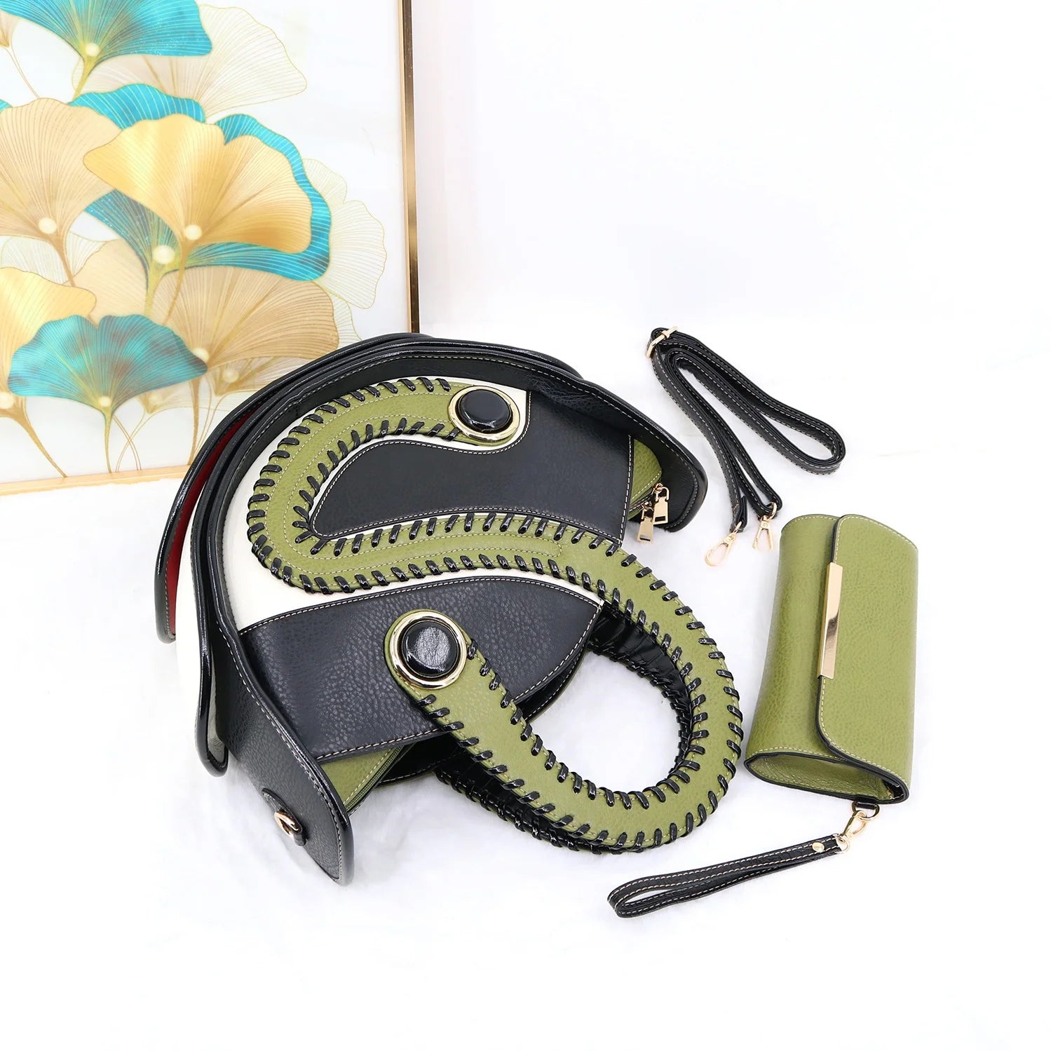Black and olive green designer handbag set, features unique contrast stitching, circular handle, and matching clutch.