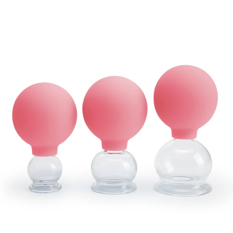 Three vacuum cupping therapy cups of varying sizes, featuring clear glass jars with pink silicone suction bulbs.