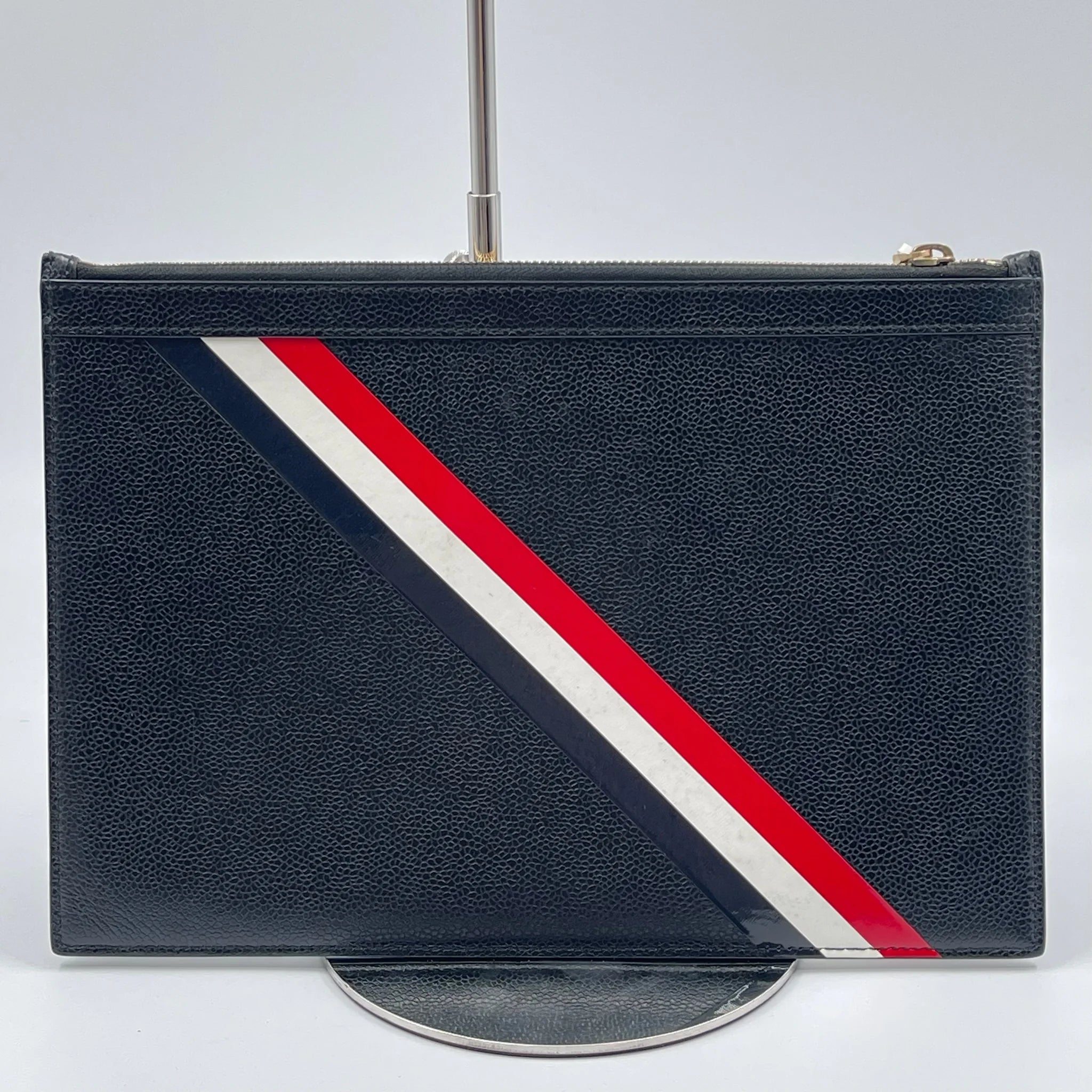 Second-hand black leather designer clutch with red, white, and blue diagonal striped detailing for travel.