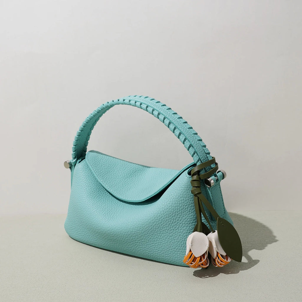 Light blue genuine leather crossbody tote with braided top handle, floral charm, and designer style.