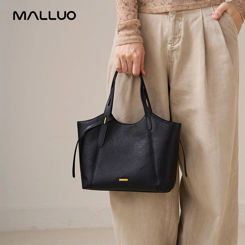 Black genuine top grain cow leather designer handbag with gold hardware, worn as a retro shoulder armpit bag.