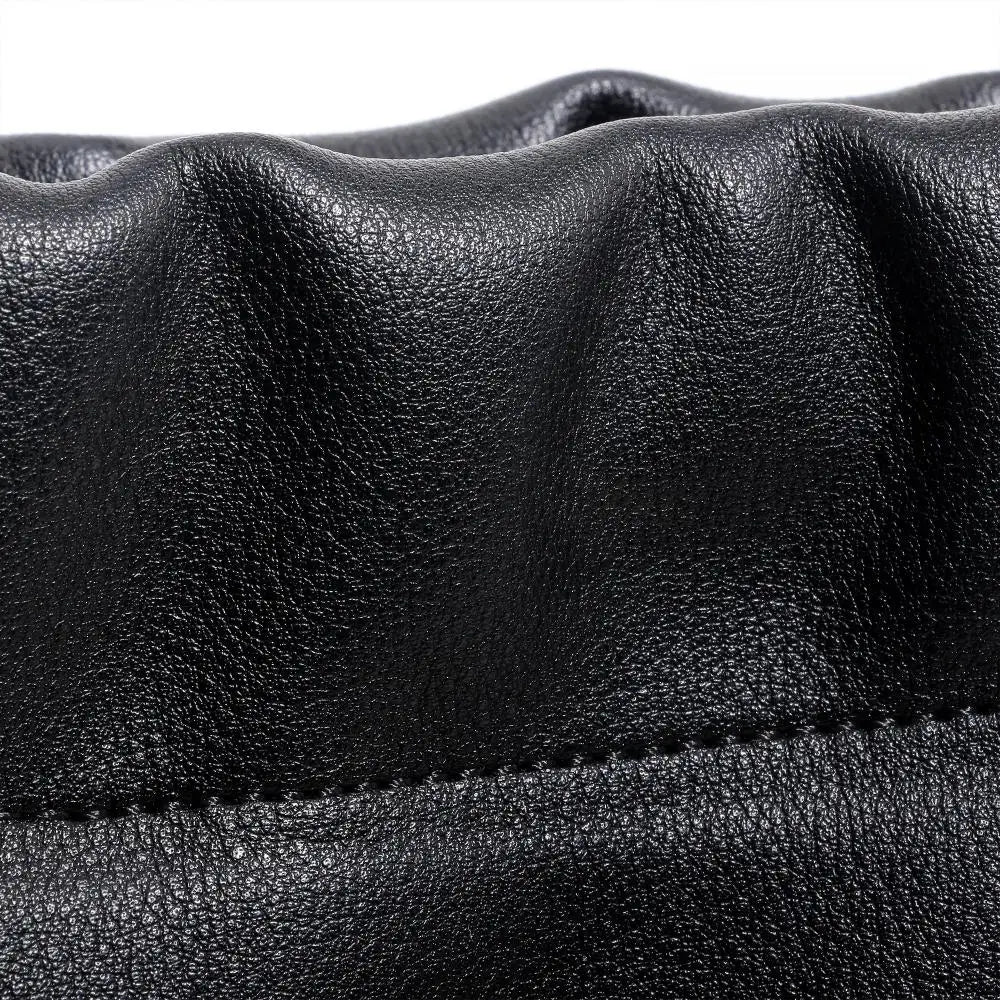 Close-up of premium black genuine leather texture with gathered details and durable stitching on a large tote handbag.