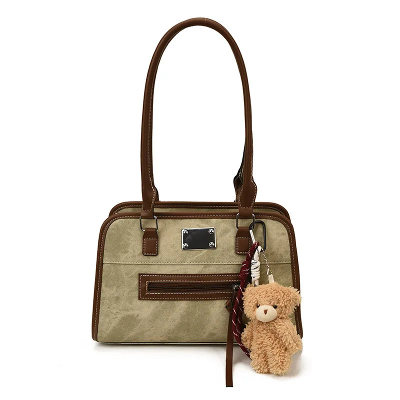 Large beige soft leather tote bag with brown trim, zipper pocket, and cute teddy bear charm. Trunks shoulder bag.