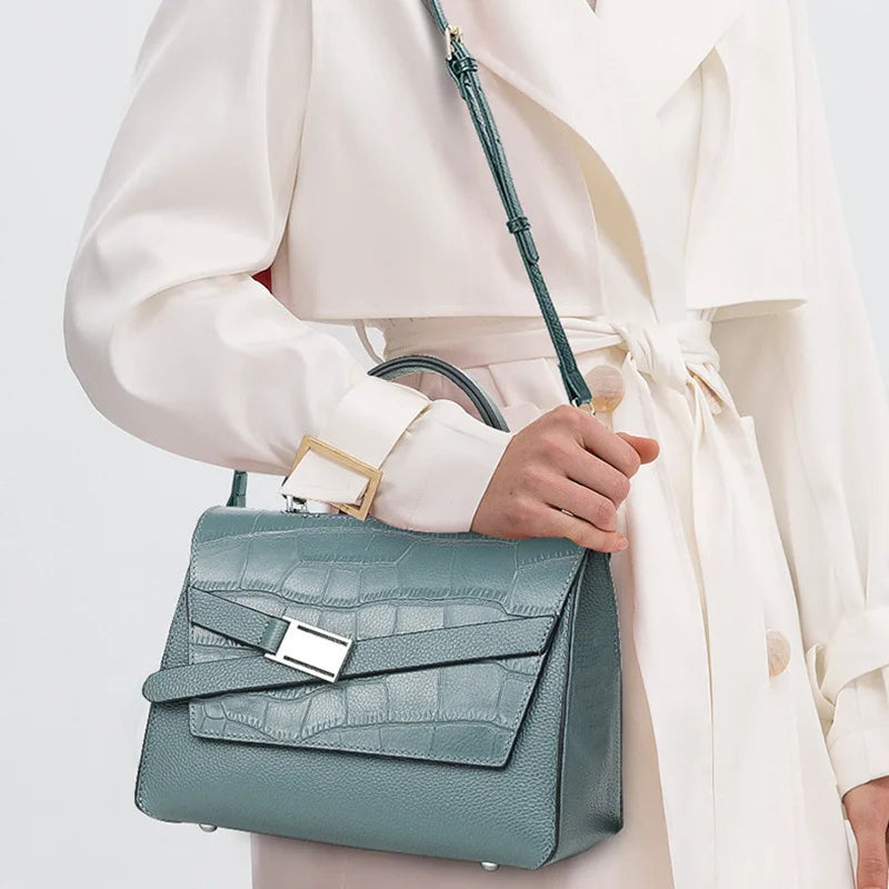 Blue-green genuine leather designer handbag with crocodile texture, top handle, and silver buckle closure.