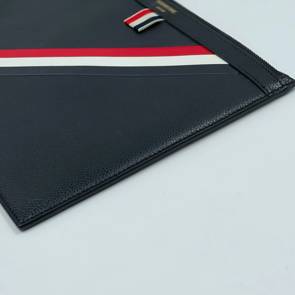 Black leather designer clutch featuring a red, white, and blue stripe geometric pattern. Stylish travel handbag.