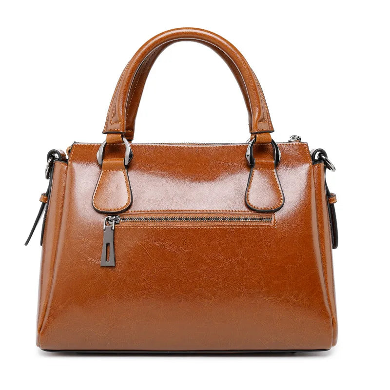 Tan cow split leather designer handbag with top handles, back zip pocket, and polished metallic hardware.