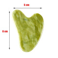 Heart-shaped light green jade gua sha facial massage tool, 5 cm wide and 8 cm long, isolated on a white background.