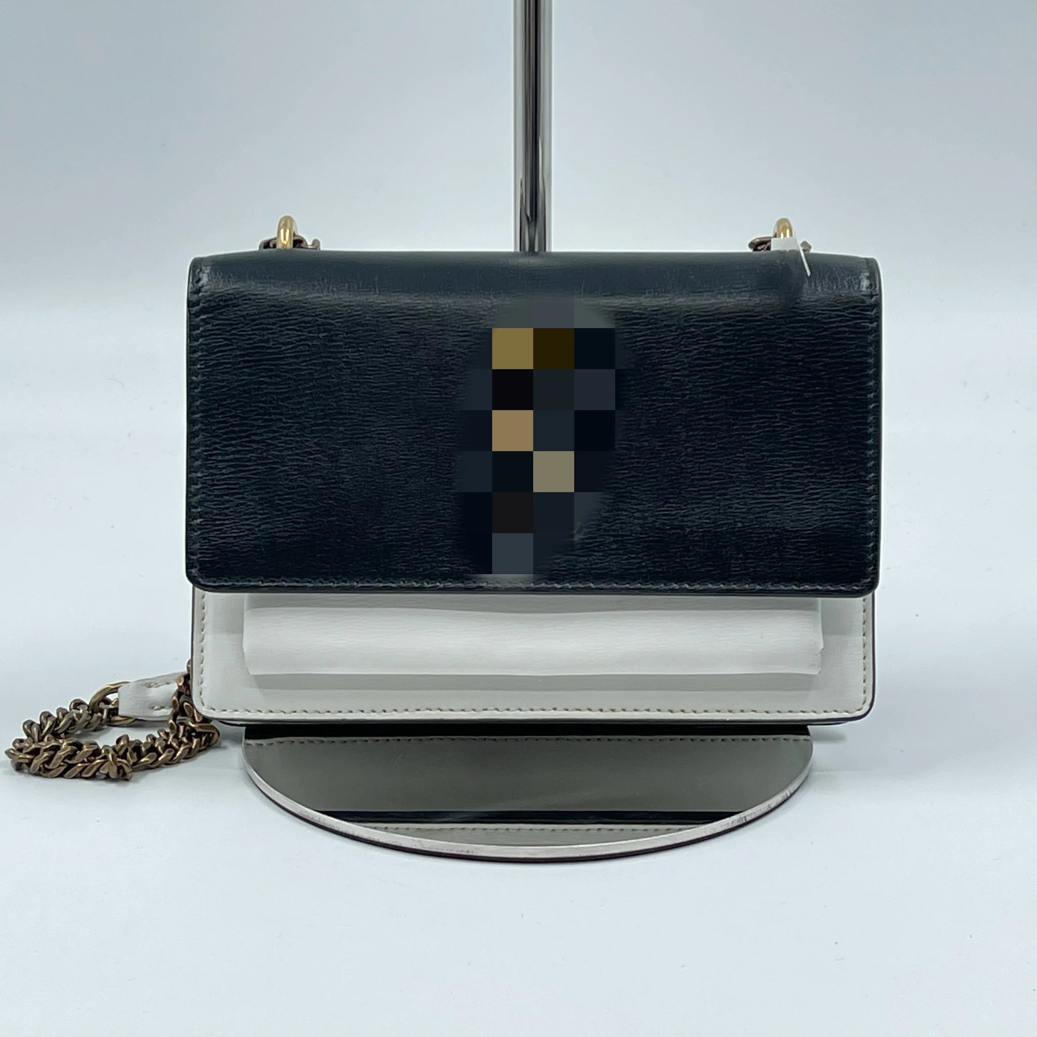 Designer black and white leather shoulder bag with a gold chain strap and snap closure, perfect for formal parties.