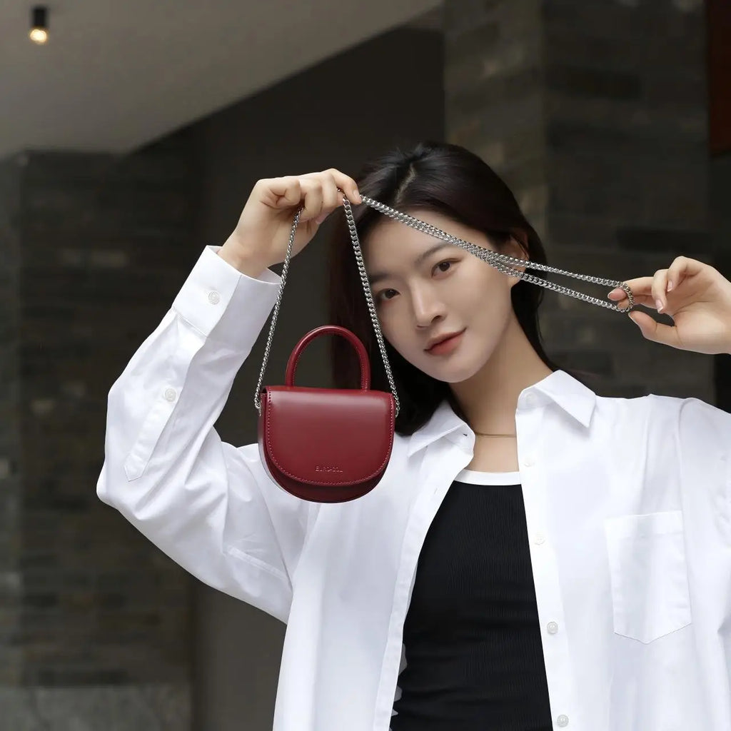 Burgundy cowhide leather mini clutch with silver chain strap and top handle. Small designer handbag for formal events.