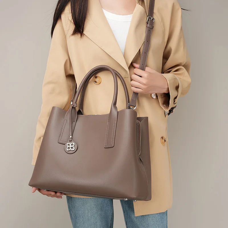 Taupe genuine leather designer handbag, large capacity tote with top handles, removable shoulder strap, and logo charm.