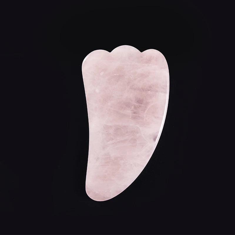 Light pink rose quartz gua sha tool with a three-pronged edge, isolated on a black background.