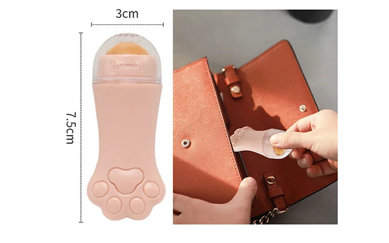 Light pink, cat-paw-shaped volcanic stone face oil roller with clear cap, held in a hand near a handbag.