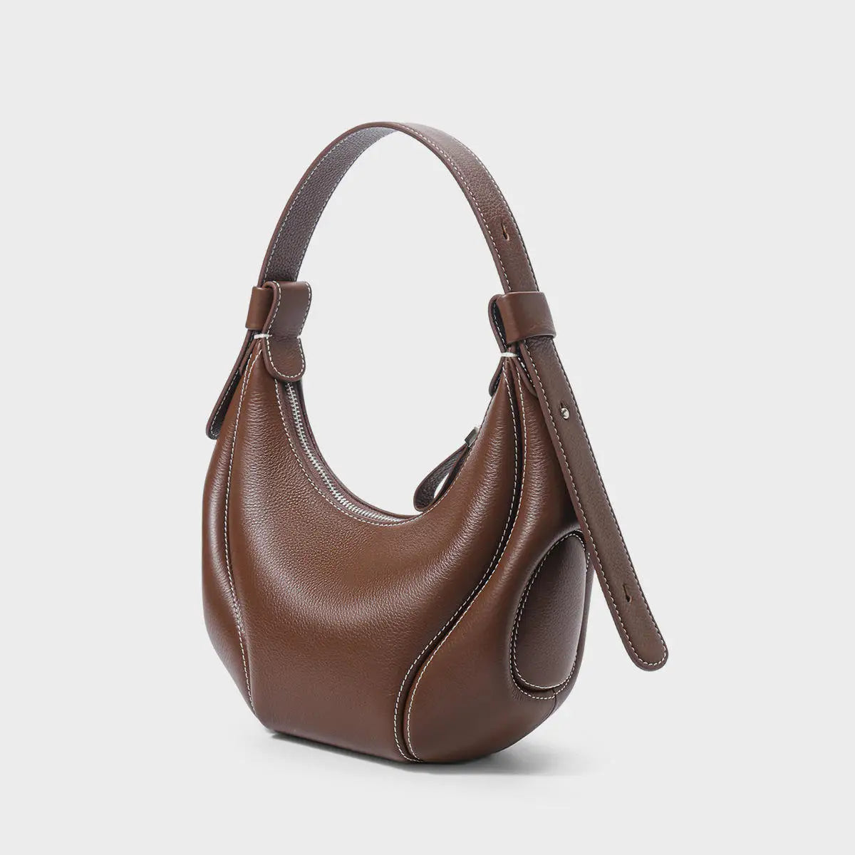 Brown leather half-moon crossbody handbag with contrast white stitching and adjustable strap. Luxury trunk-style design.