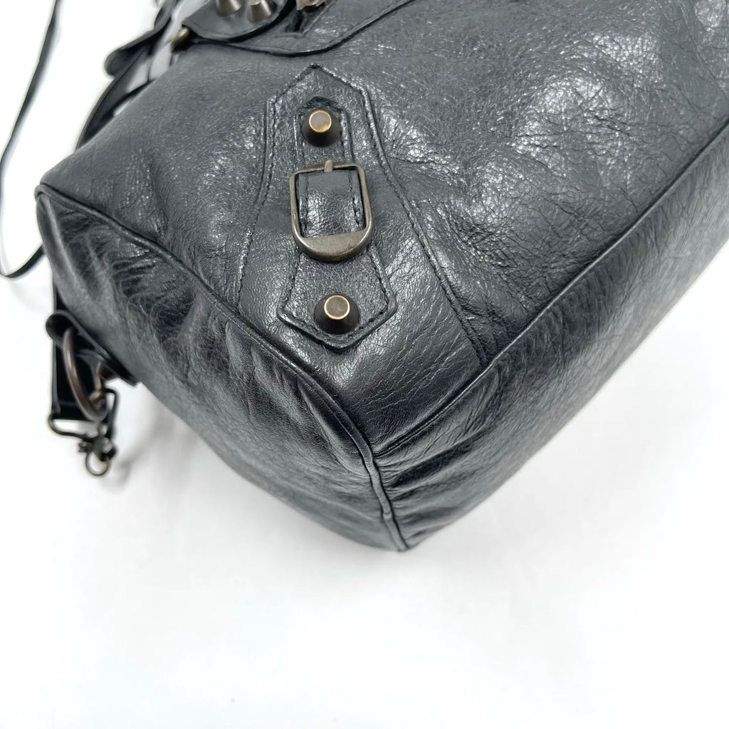 Black genuine leather designer handbag, pillow-shaped tote with vintage buckle hardware and distressed texture.