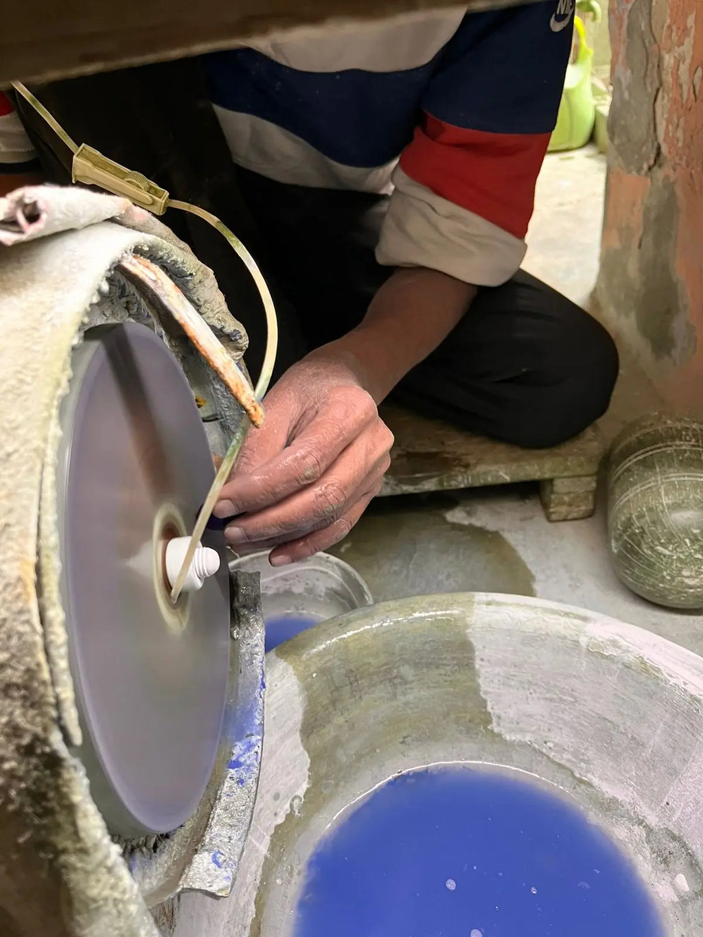 Cabochon gemstone being polished on a rotating grinding wheel