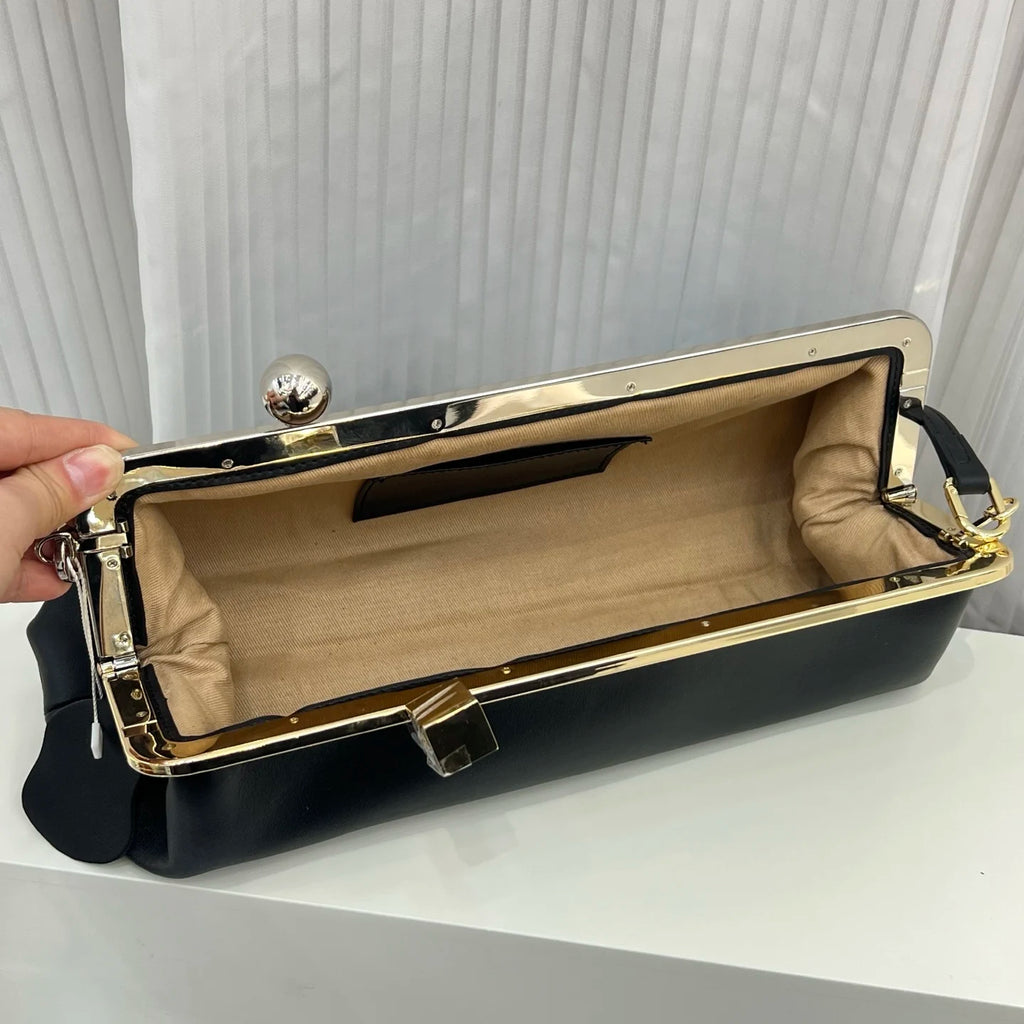 Black leather designer shoulder bag with a gold metal frame, sphere clasp, and beige interior lining.