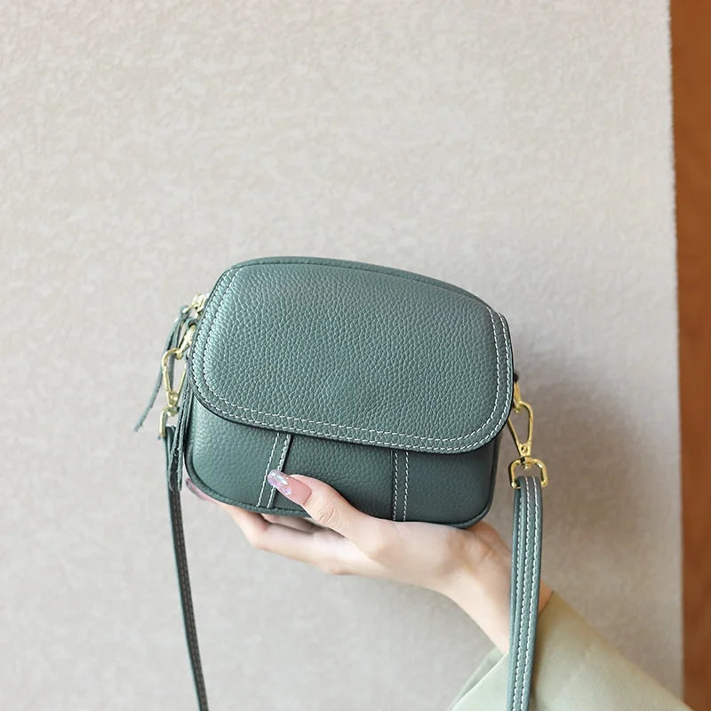 Green pebbled leather designer mini crossbody bag with gold hardware, white contrast stitching, and adjustable strap.