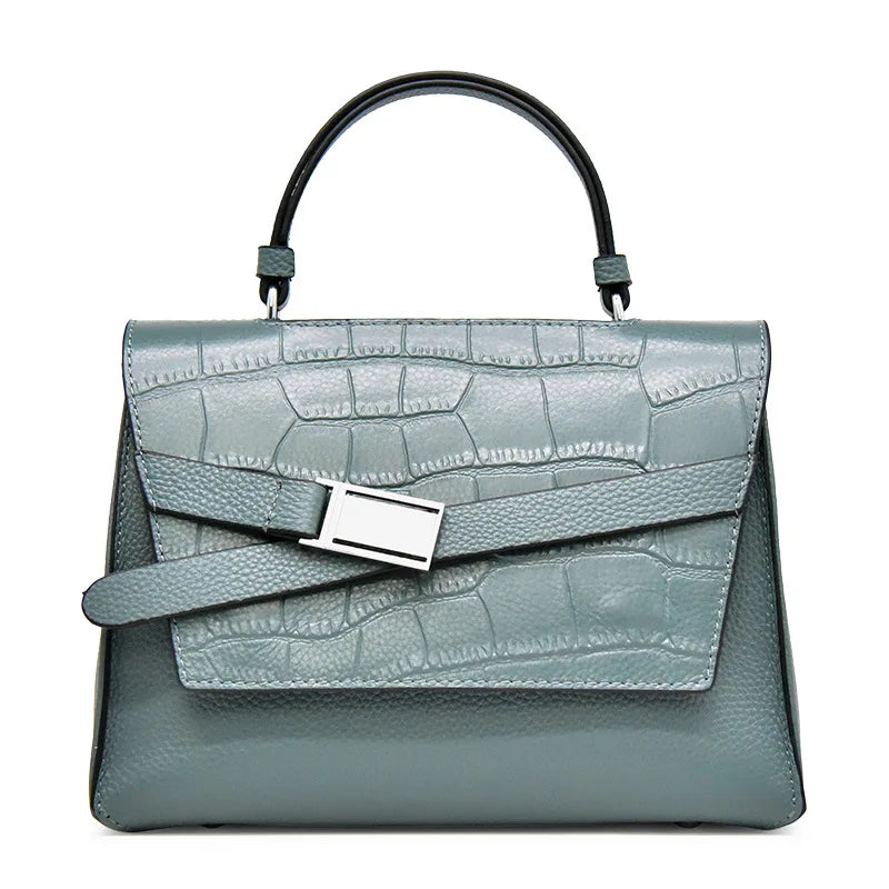 Blue-grey designer leather handbag with crocodile texture, top handle, and silver buckle strap detail.