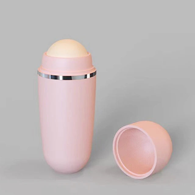 Pink, oval-shaped facial oil-absorbing roller with a round, cream-colored volcanic stone and a removable cap.